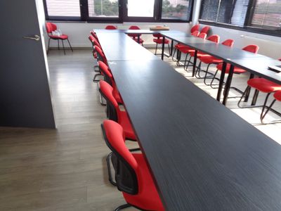 une longue table avec des chaises rouges au milieu d'une pièce