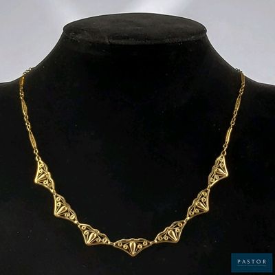 collier plaqué or avec un motif géométrique, présenté autour du cou d'un mannequin