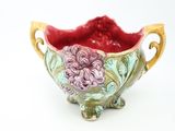 a small bowl with a flower on it on a white surface