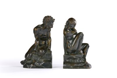 une paire de sculptures en bronze représentant un homme et une femme assis sur un rocher