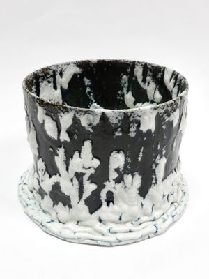 un gros plan d'un vase noir et blanc posé sur une surface blanche