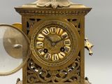 a gold clock with a magnifying glass in front of it
