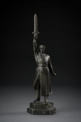 a bronze statue of a man holding a sword on a pedestal