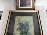 deux photos encadrées de fleurs dans un vase sur une table