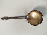 une cuillère en argent avec un manche sur une surface blanche