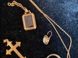 un collier en or orné d'une croix, d'une bague, d'une autre bague et d'une croix