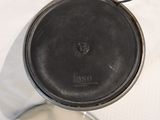 a black pan with a handle on a white surface
