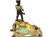 bronze figurine of a boy on a boat with a dog on a leash