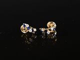 une paire de boucles d'oreilles en or et saphir posées sur un fond noir
