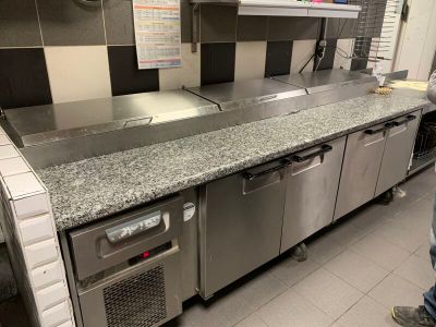 un homme debout dans une cuisine, près d'un plan de travail