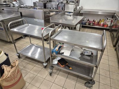 de nombreuses tables en acier inoxydable dans une cuisine, sur lesquelles sont posés de nombreux objets