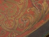 a close up of a red and gold table with a clock on top of it
