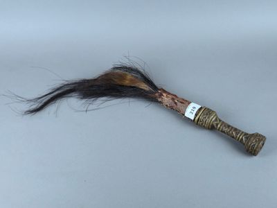 un bâton surmonté d'une plume, posé sur une table