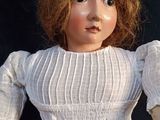 a close up of a doll wearing a white dress and a flower crown