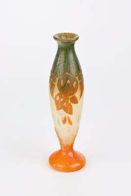 un vase orange et vert posé sur une surface blanche