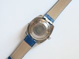 someone is holding a watch on their wrist on a white surface