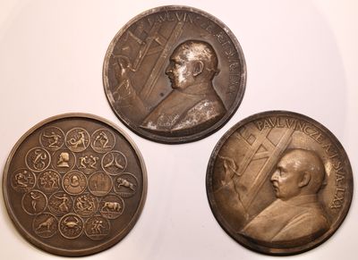 three bronze medallions of a man and a woman on a white surface