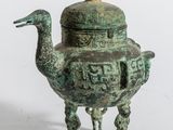 une vieille théière en bronze surmontée d'un oiseau
