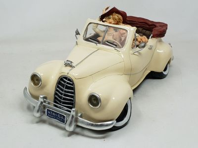 une figurine représentant une femme au volant d'une voiture, avec un chien sur la banquette arrière