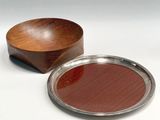 a wooden bowl and a silver plate on a white surface