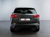 the rear end of a grey car in a white room