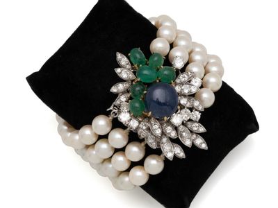 une image représentant une bague ornée de perles et d'émeraudes, posée sur une serviette noire