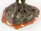 bronze statue of a man holding a soccer ball on a marble base