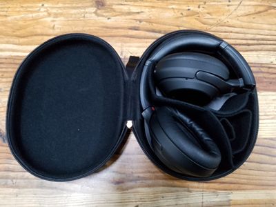 un casque audio dans son étui, posé sur une table en bois