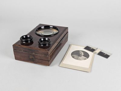 une vieille photo représentant une boîte en bois sur laquelle est posée une loupe
