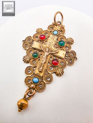 un gros plan sur une croix accrochée à un collier, portée par un mannequin