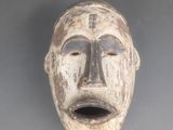 une image d'un masque en bois accroché au mur
