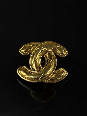 a chanel gold plated brooch with a circular design