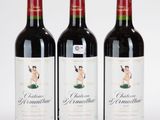 trois bouteilles de vin rouge posées l'une à côté de l'autre sur une surface blanche