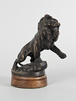 statue en bronze représentant un lion, posée sur un socle en bois, sur fond blanc