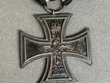 an iron cross medal with a gold ribbon on a gray surface