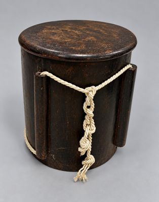 an old wooden box with a rope around it on a gray surface