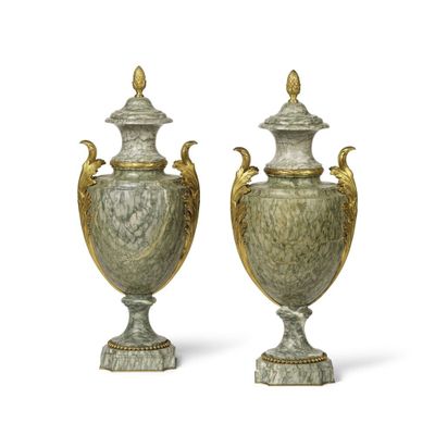 une paire de vases verts et dorés posés sur des socles, sur fond blanc