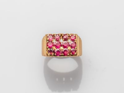 a gold ring with pink stones on a white surface