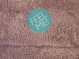brown towel with a blue sticker that says feel me on it