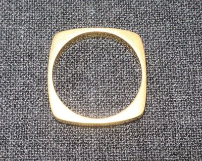 un gros plan d'une bague en or posée sur un tissu gris