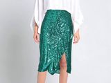 une femme vêtue d'une chemise blanche et d'une jupe verte à paillettes