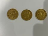 three gold coins sitting next to each other on a white surface