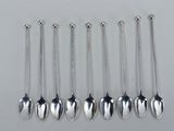 six cuillères en argent avec des chaînes qui pendent, posées sur une table