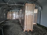de nombreuses piles de bois dans un entrepôt, posées sur des palettes
