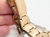 a person holding a watch in their hand on a white surface
