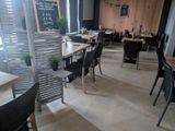 tables and chairs in a restaurant with a chalk board on the wall