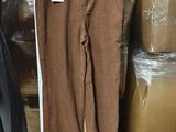 un pantalon en velours côtelé marron suspendu à un cintre devant des cartons