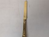 a gold plate with a knife on it sitting on top of a table