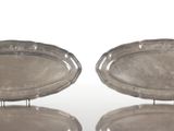 trois plateaux en argent posés sur un support, sur une surface blanche