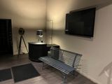 a bench in the corner of a room with a tv on the wall